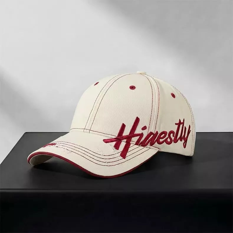 Ivory cotton baseball cap with red embroidery and contrast stitching.