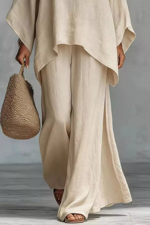 Beige polyester two-piece set with flowing top and wide-leg pants with side slits.