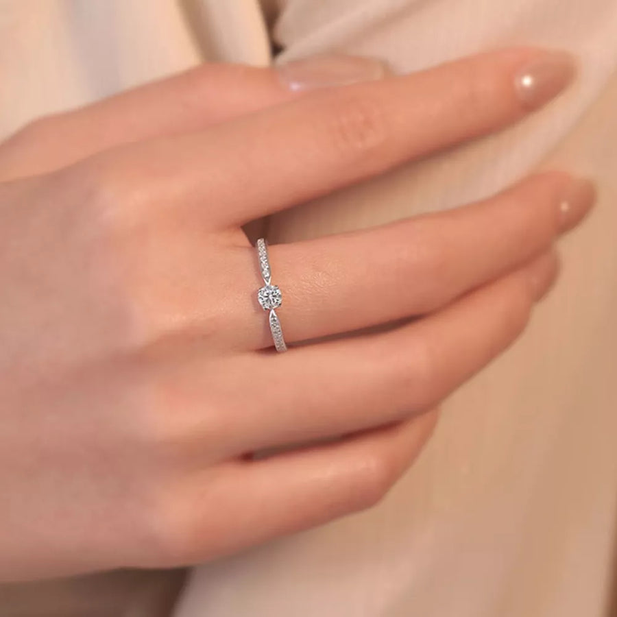 Elegant moissanite ring in sterling silver with a brilliant center stone and pave band.