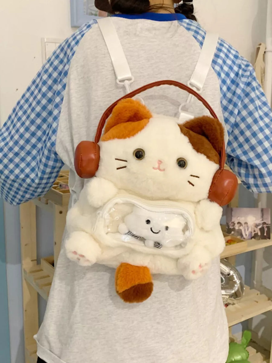 White plush cat backpack with brown and orange accents and a clear front pocket.