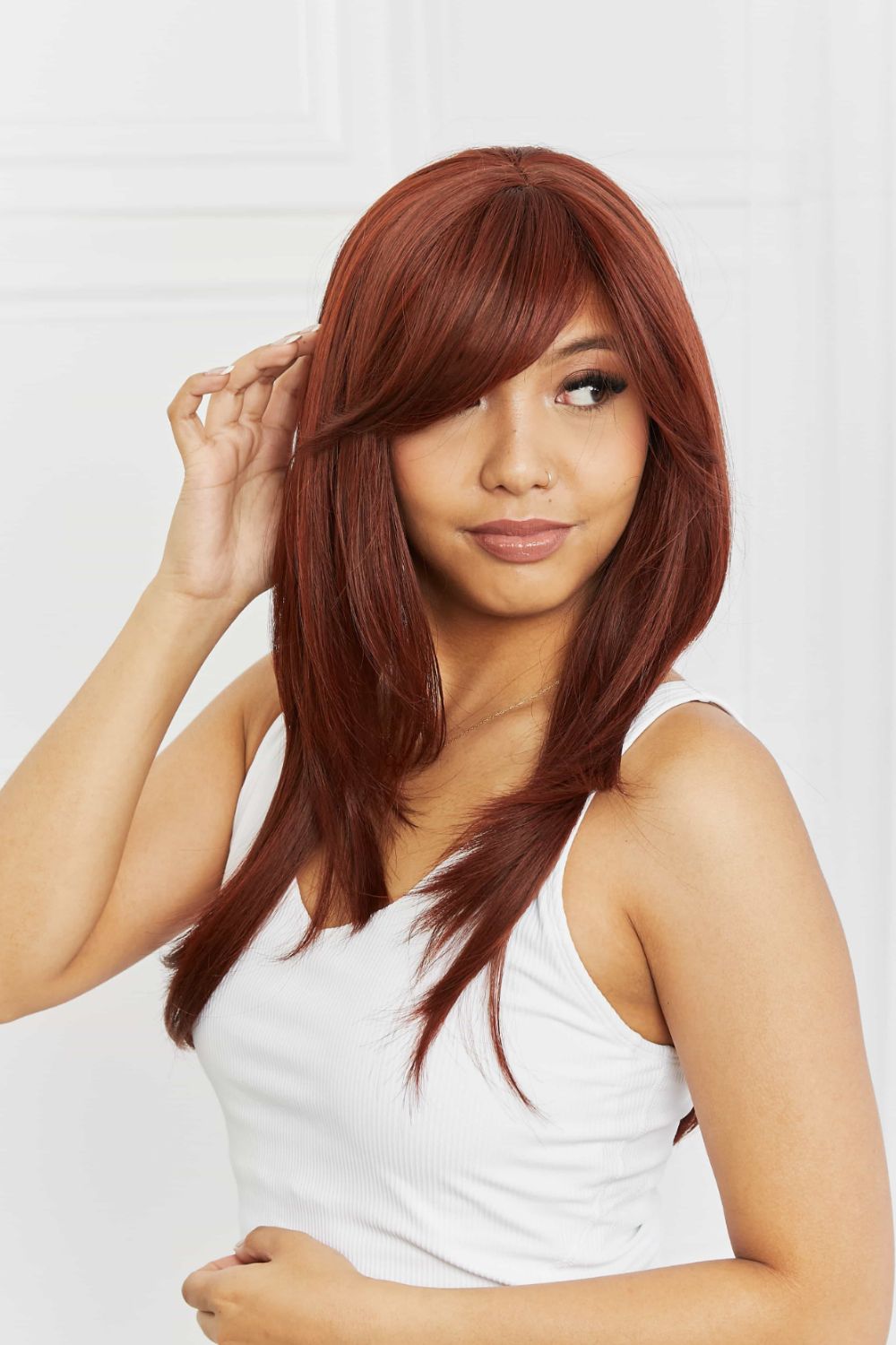Layered copper red synthetic wig with chic bangs and face-framing layers.