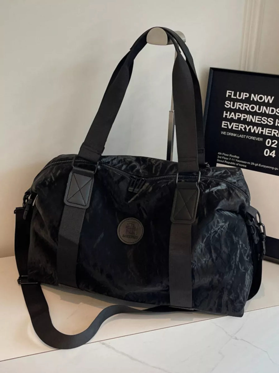 Black medium oxford cloth travel bag with adjustable strap and round logo detail.