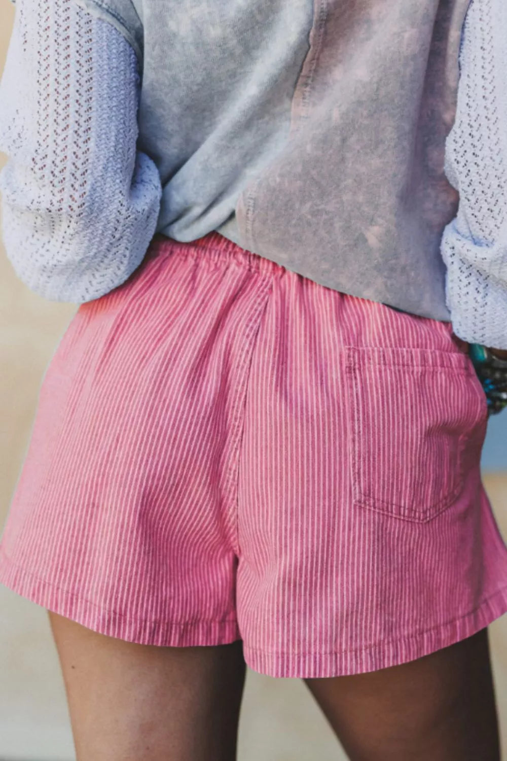 Pink striped denim shorts with drawstring waist and back pocket detail.