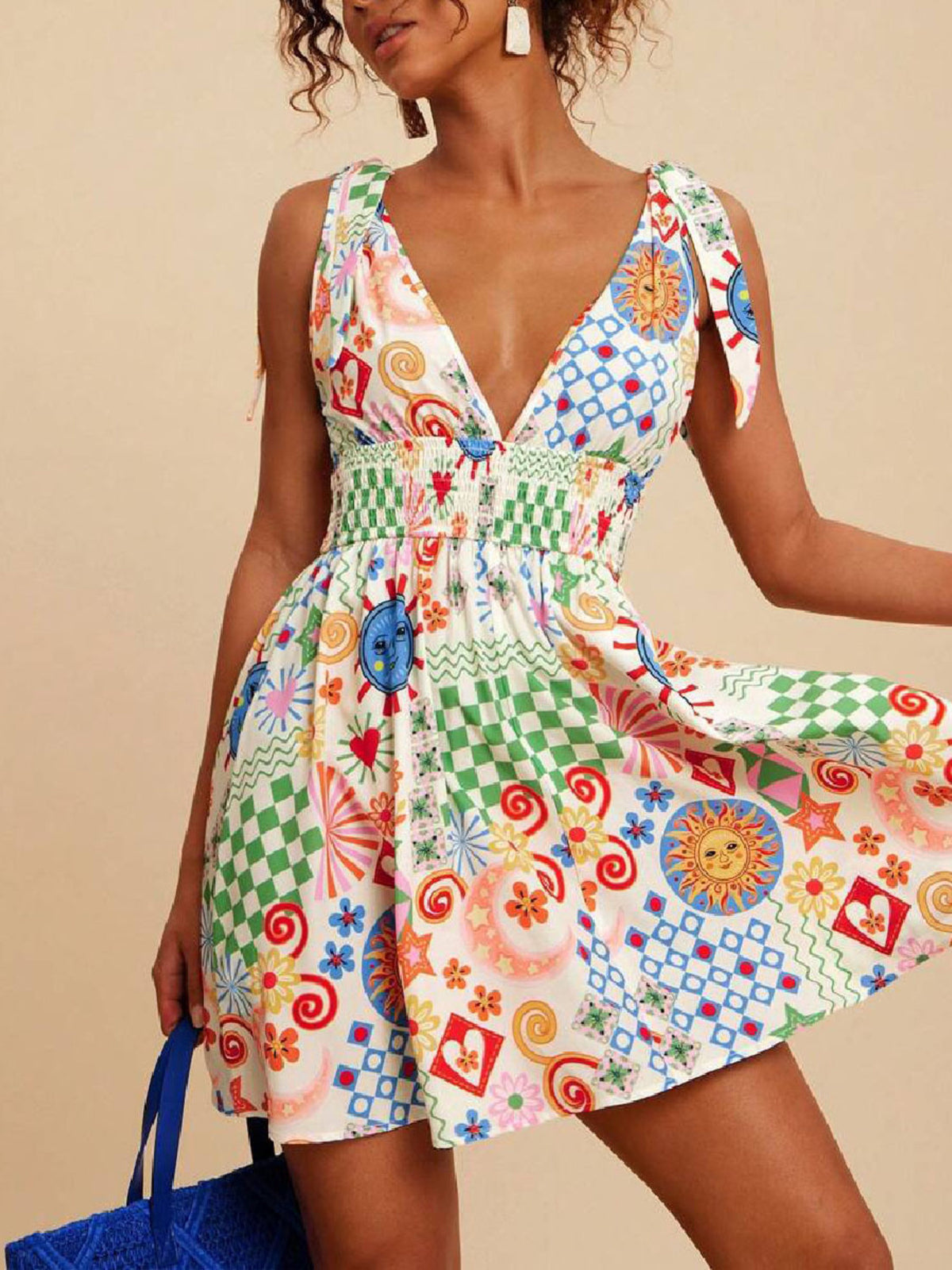 Playful printed mini dress with tied straps, V-neck, smocked waist, and colorful sun and checkered patterns.