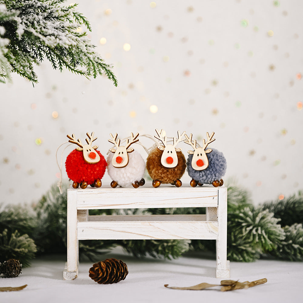 Four multicolor pom-pom reindeer Christmas ornaments with wooden antlers and red noses.