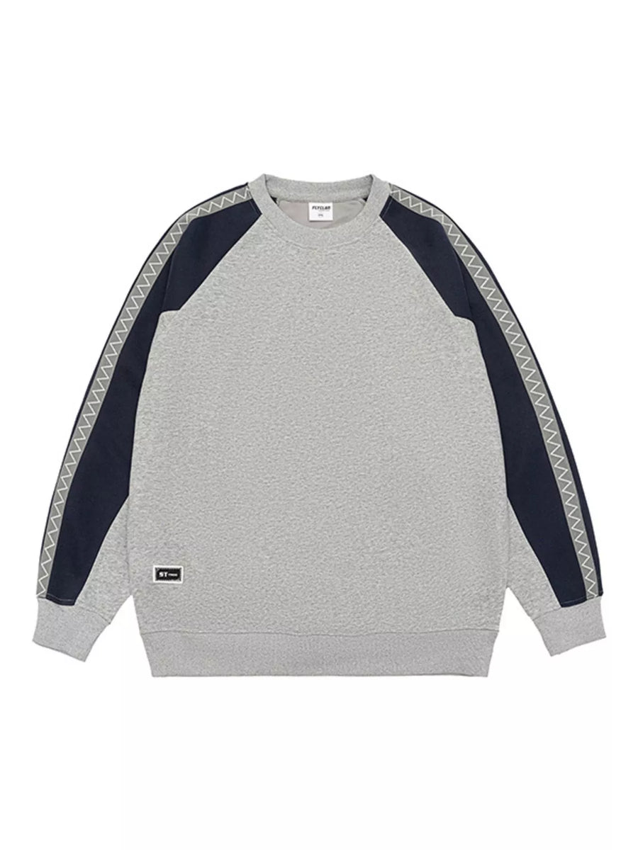 Oversized gray raglan sleeve sweatshirt with navy panels and zigzag trim detail.