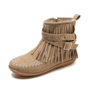 Beige suede ankle boots with fringe, studs, and buckle strap detail.