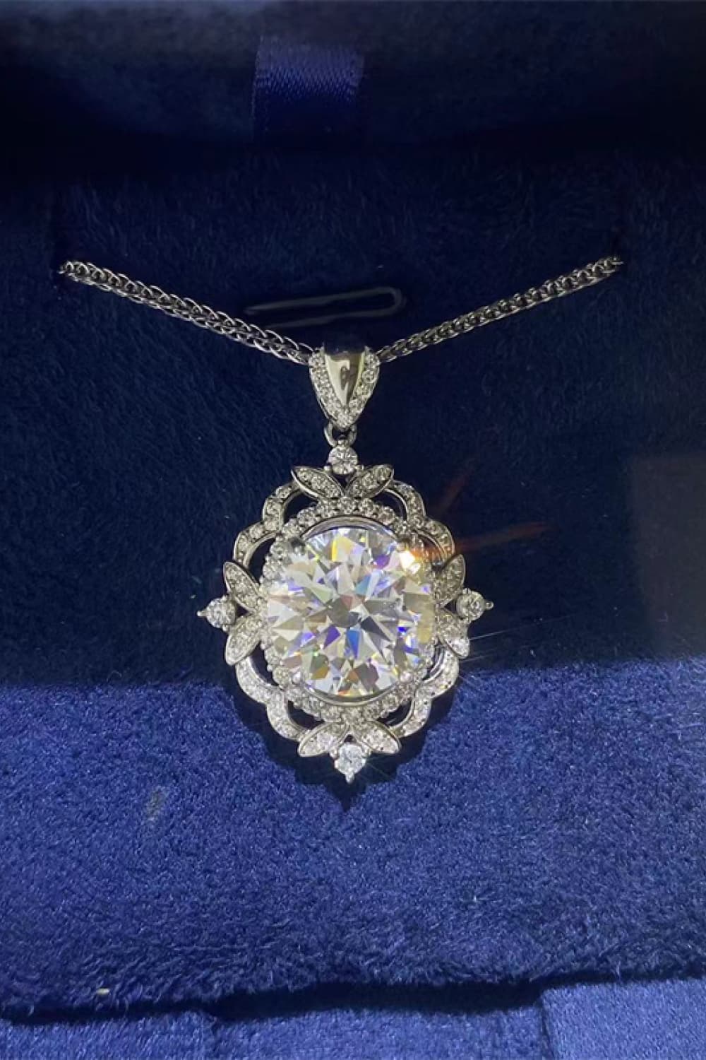 Silver filigree halo diamond pendant necklace with a large center stone and intricate detailing.