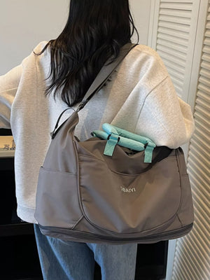 Spacious gray Oxford cloth travel duffel bag with teal handles and exterior pockets.