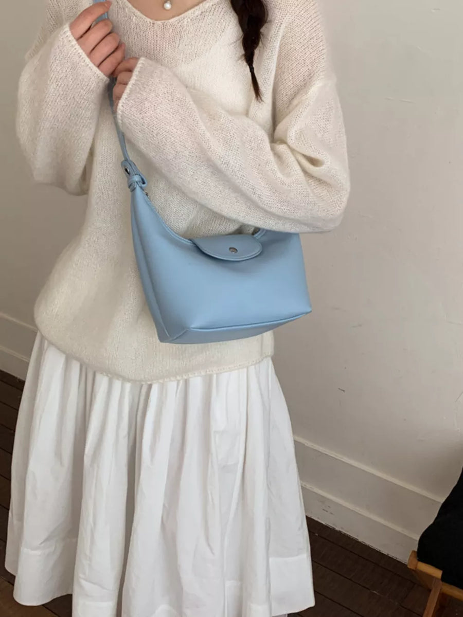 Blue mini crescent hobo bag with flap closure and adjustable strap.
