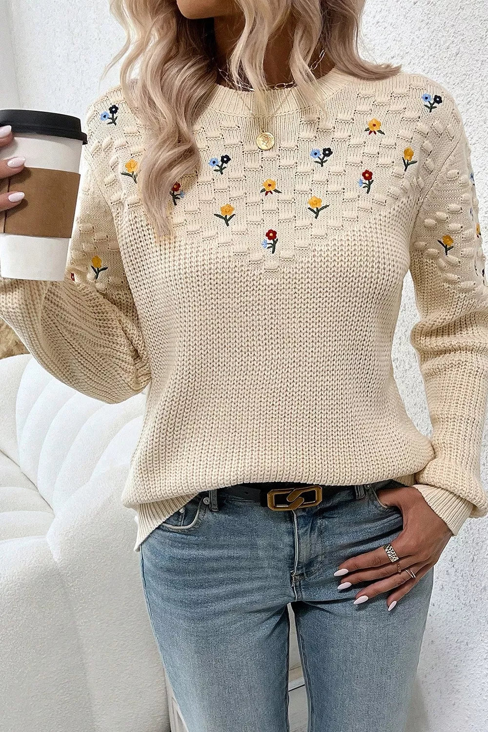 Beige embroidered round-neck sweater with dropped shoulders and textured sleeves.
