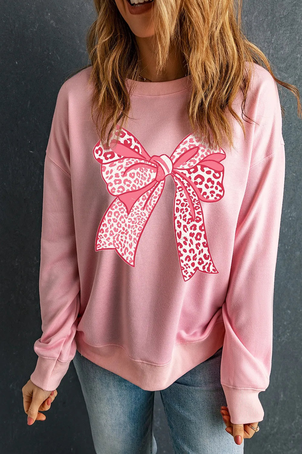 Blush pink crewneck sweatshirt with a large pink leopard print bow graphic on the front.