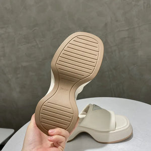 Ivory platform slides with geometric sole detail and branding.