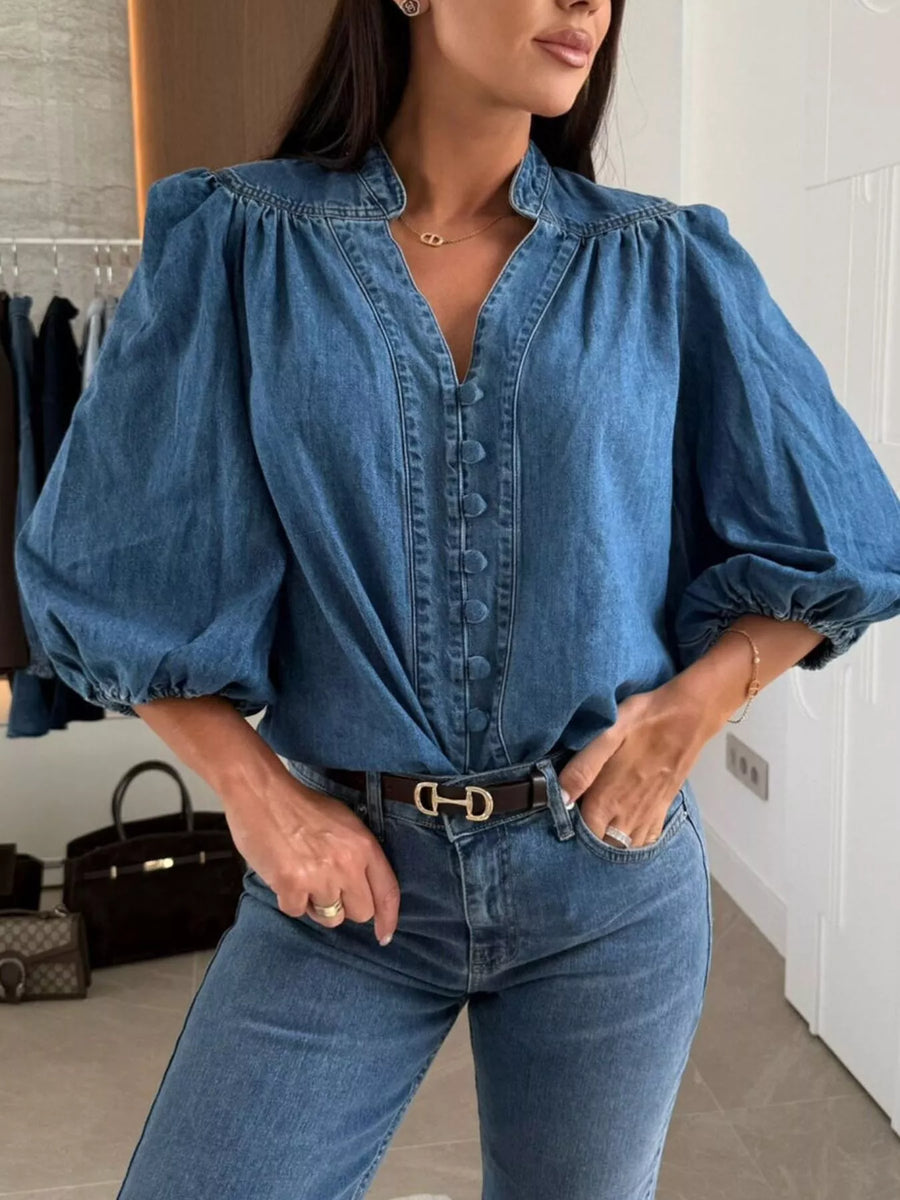 Denim button-down blouse with puff sleeves and a V-neckline in dark blue.