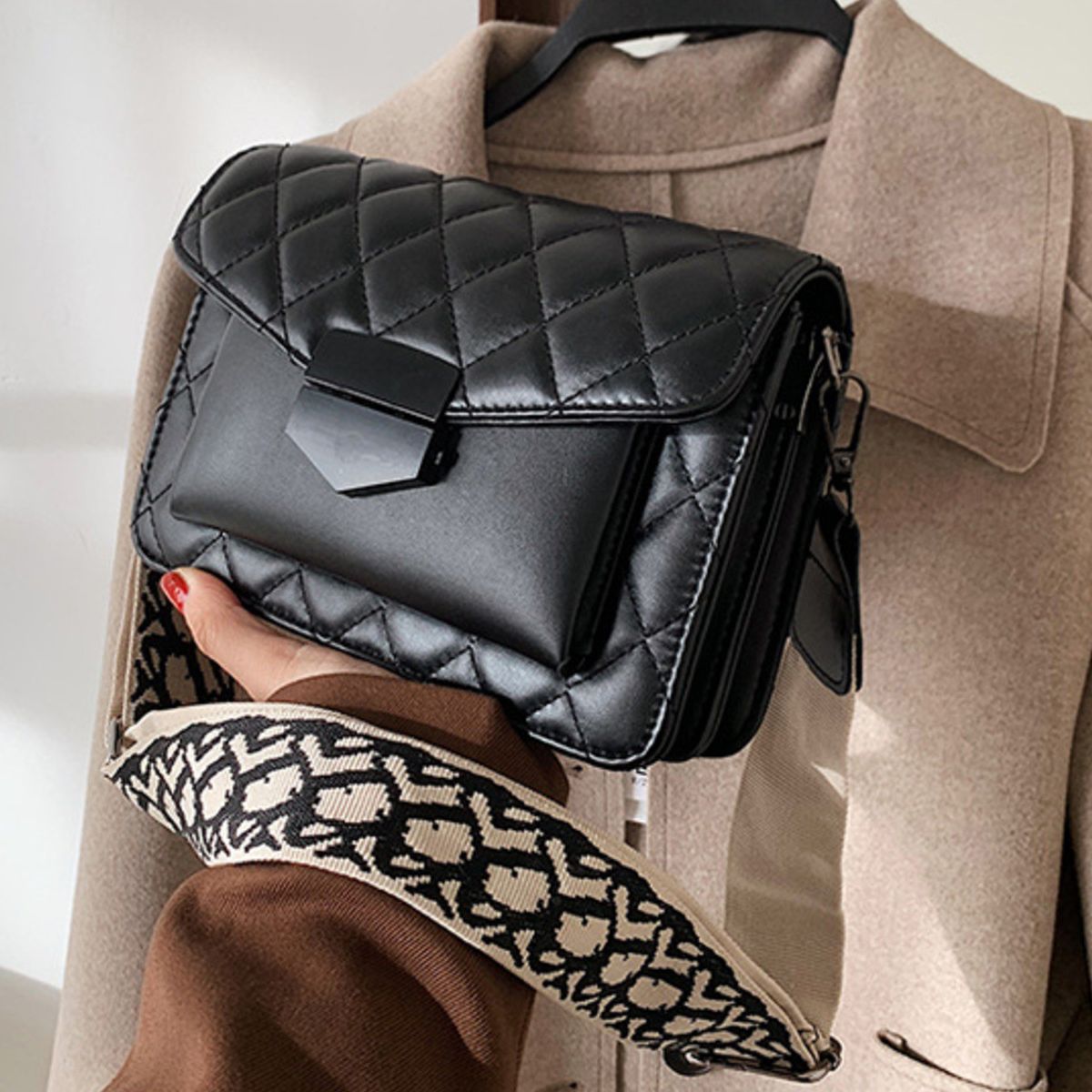 Chic quilted flap crossbody bag in black with a patterned strap and gold hardware.