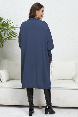 Dark blue cardigan with balloon sleeves and a long hem, worn by a model.
