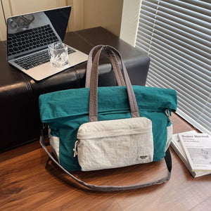 Duffel bag in teal and white with grey straps and a front pocket.