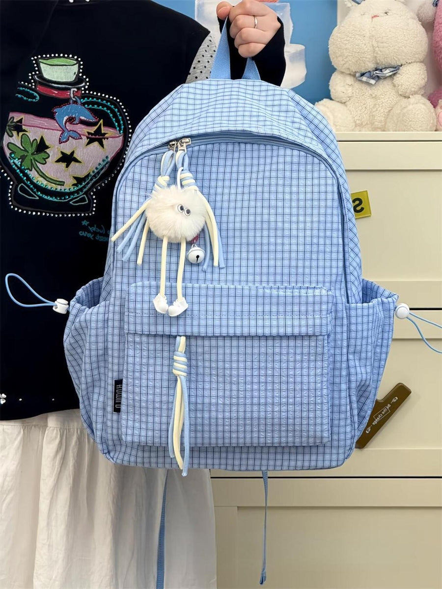 Blue plaid medium nylon school backpack with fuzzy charm and tassel detail.
