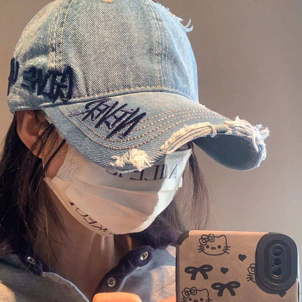 Denim baseball cap with dark embroidery and distressed details.