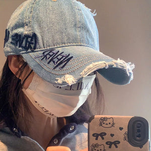 Denim baseball cap with dark embroidery and distressed details.