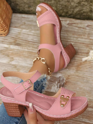 Pink laser-cut detail block heel sandals with buckle strap and gold accents.