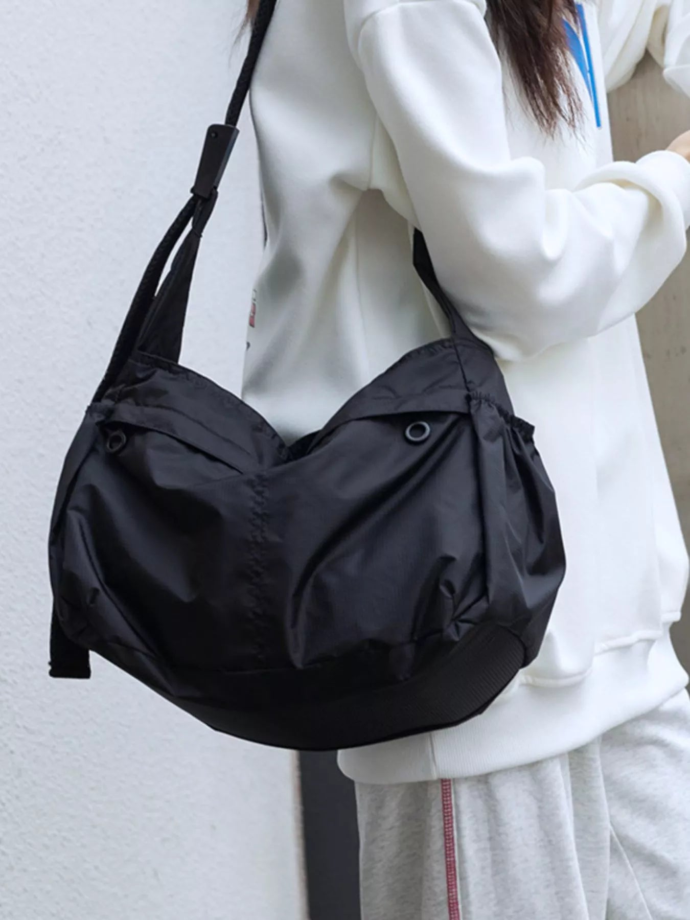 Spacious black nylon crossbody bag with adjustable strap and exterior pockets.