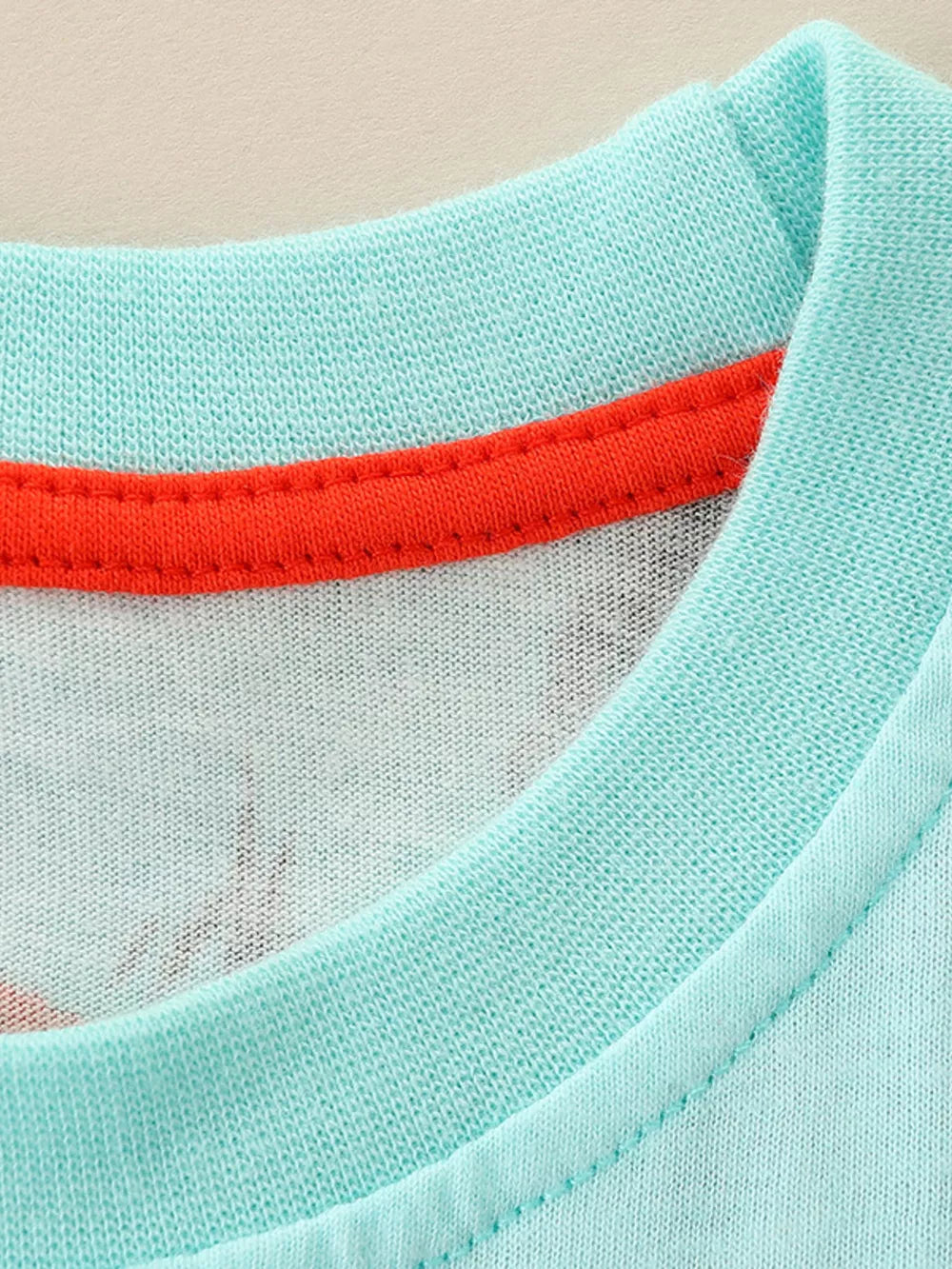 Toddler graphic tee in light blue cotton with orange trim and a subtle dino print.