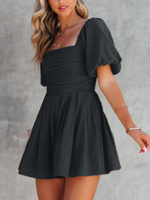 Black ruched puff sleeve square neck romper with gathered waist and flared skirt.