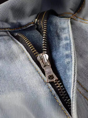 Light wash denim jeans with a distressed look and silver zipper detail.