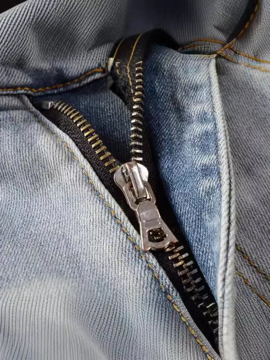 Light wash denim jeans with a distressed look and silver zipper detail.