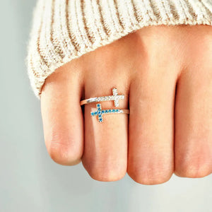 Sterling silver ring with two intertwined crosses, one with clear stones and one with blue stones.