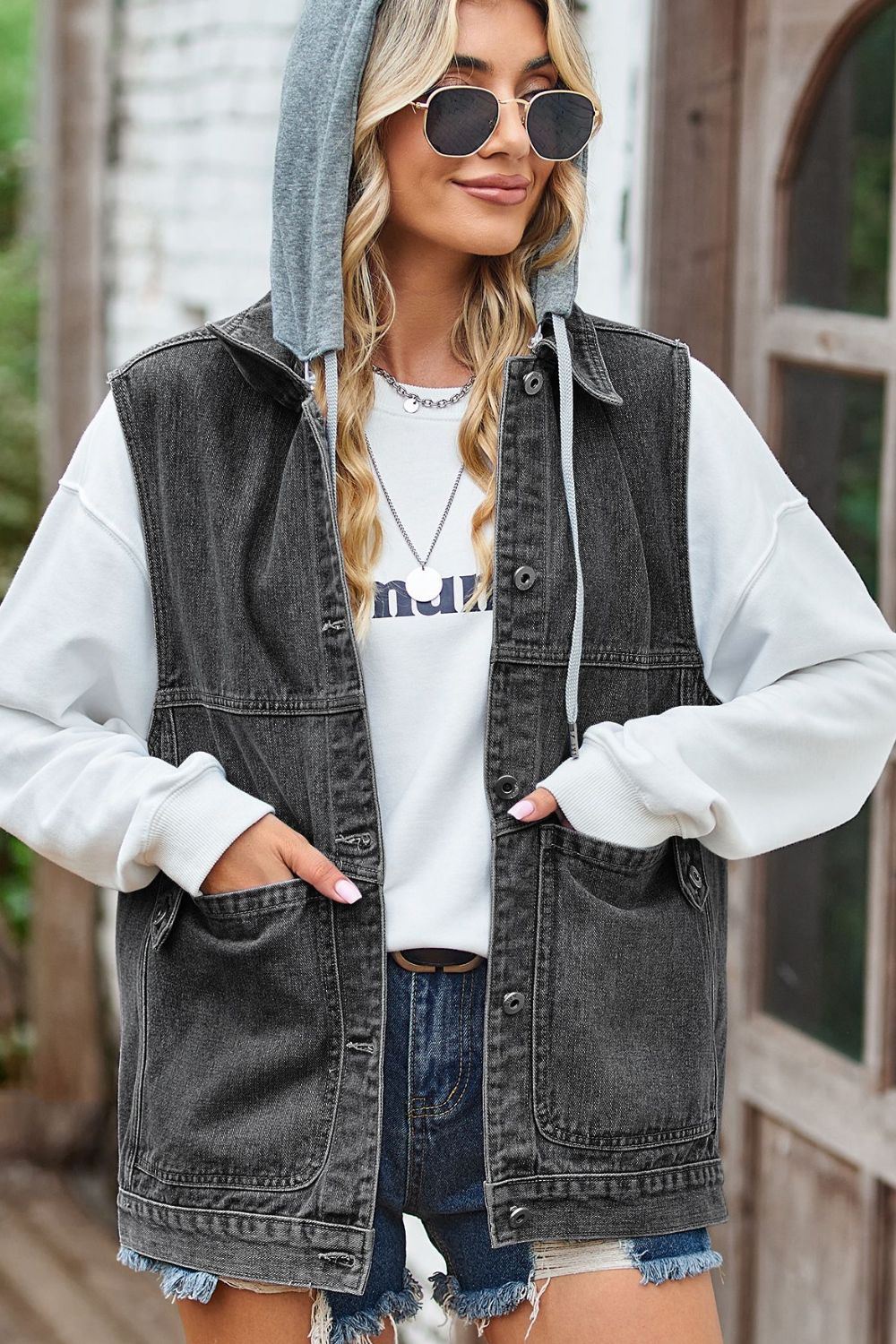 Dark denim hybrid vest with detachable grey hood, button front, and chest pockets.