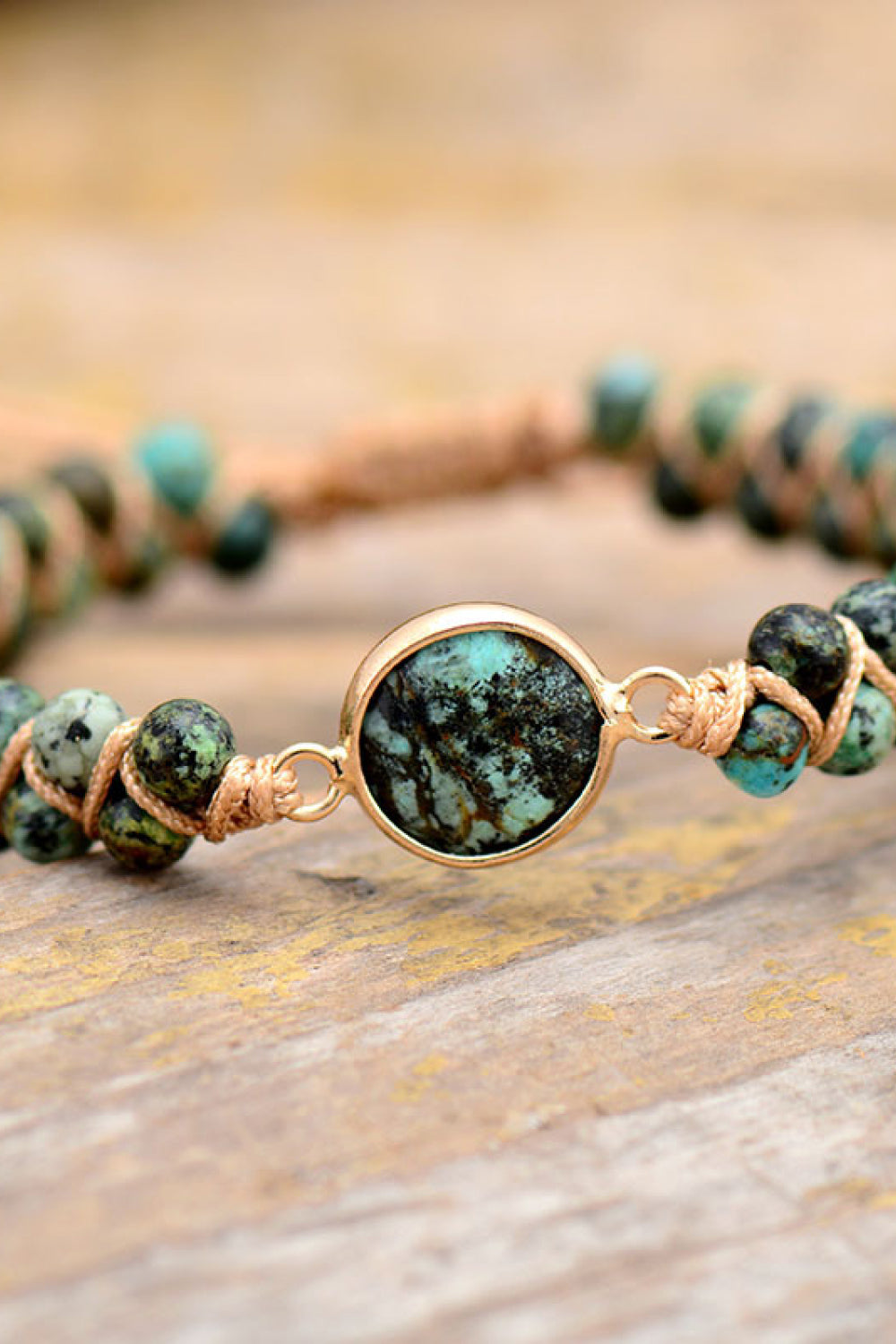 Turquoise beaded bracelet with braided cord and gold-tone center stone detail.