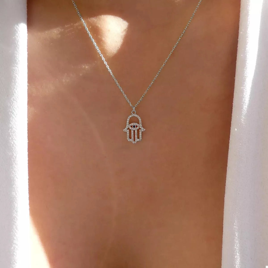 Silver Evil Eye Hamsa necklace with rhinestone details.