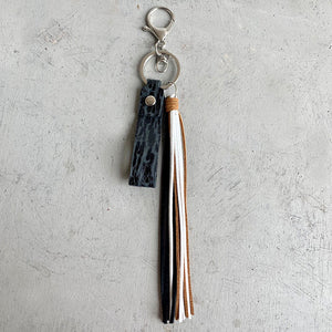 Textured leather tassel keyring with black, white, and brown tassels and silver hardware.