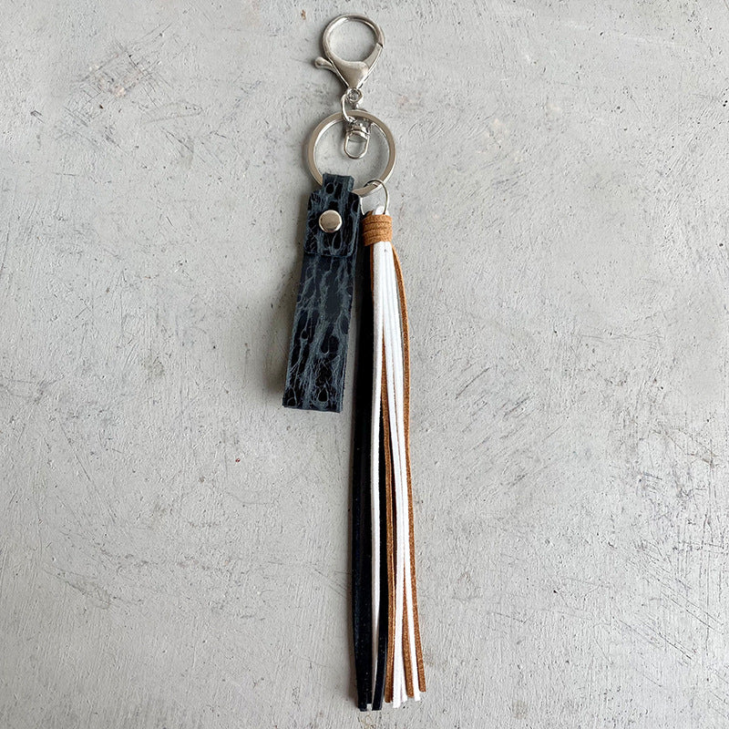 Textured leather tassel keyring with black, white, and brown tassels and silver hardware.