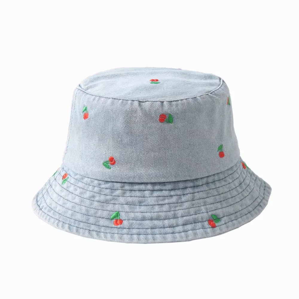Light wash denim bucket hat with allover red cherry embroidery and stitched brim detail.