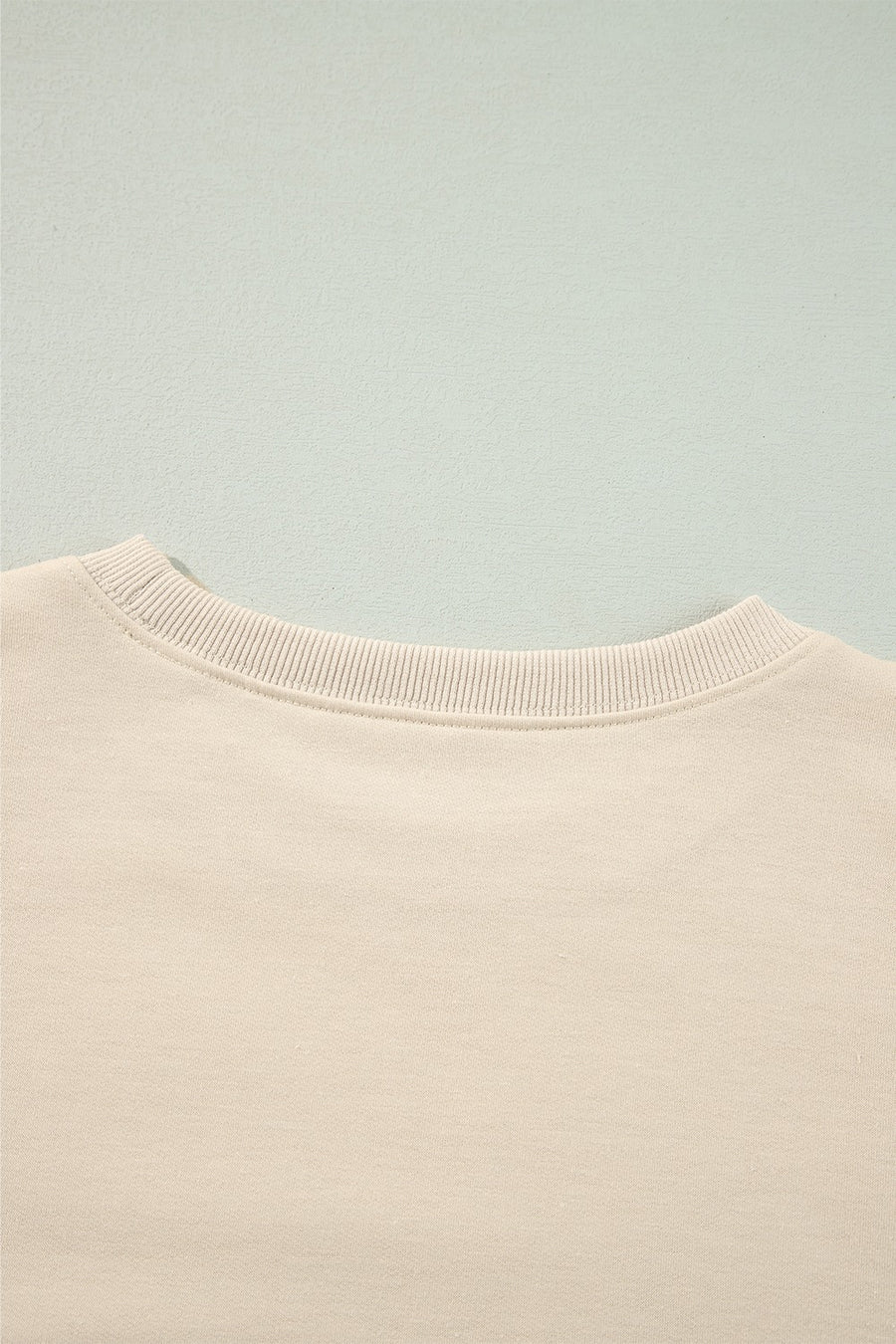 Cream sweatshirt with ribbed neckline and subtle shoulder ruffles.