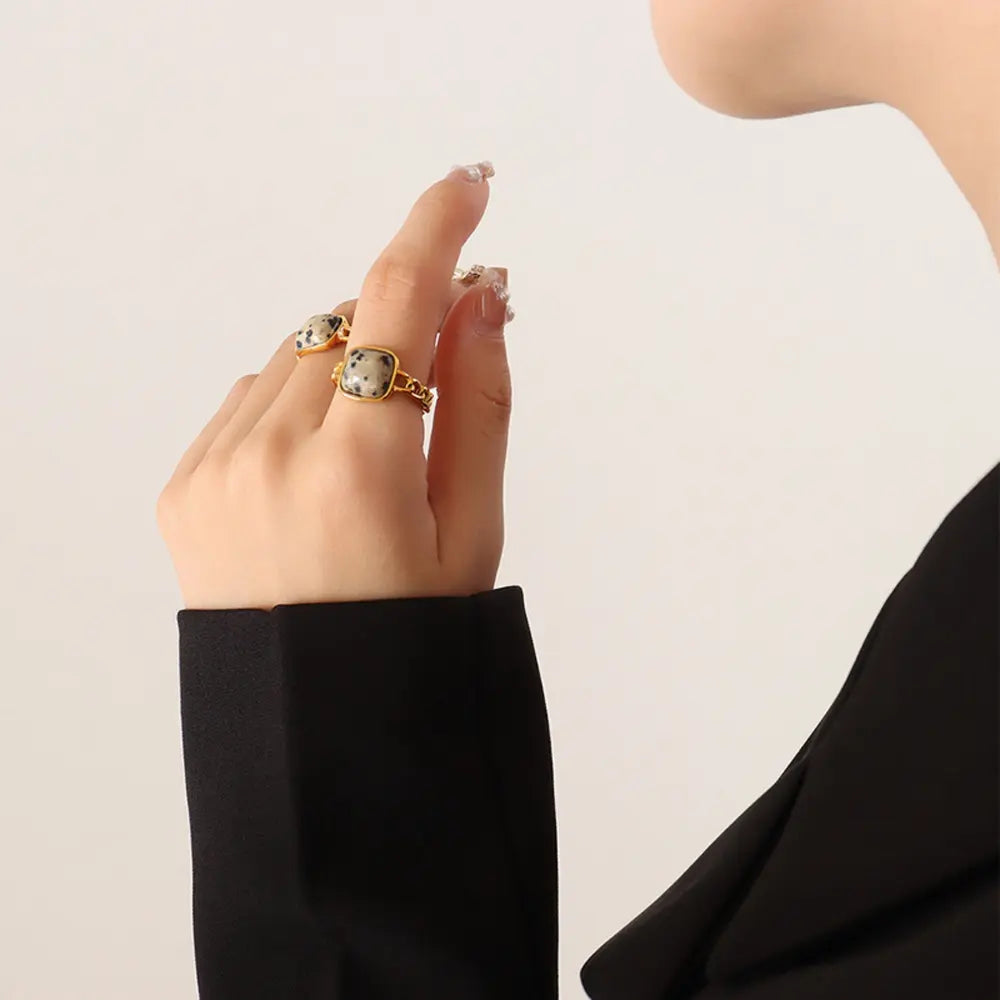 Gold ring with square natural stone inlay and chain detail on finger