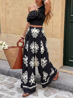 Black one-shoulder ruffled crop top with black and white printed wide-leg pants.