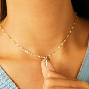 Gold beaded necklace with a small cross pendant and colorful bead accents.