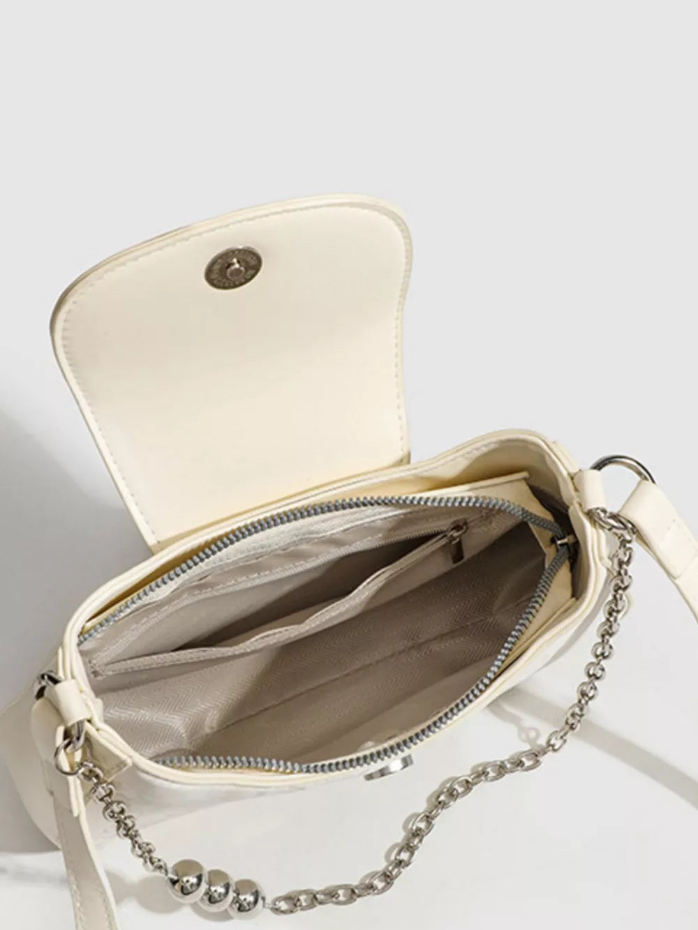 White mini shoulder bag with chain strap and interior pockets.