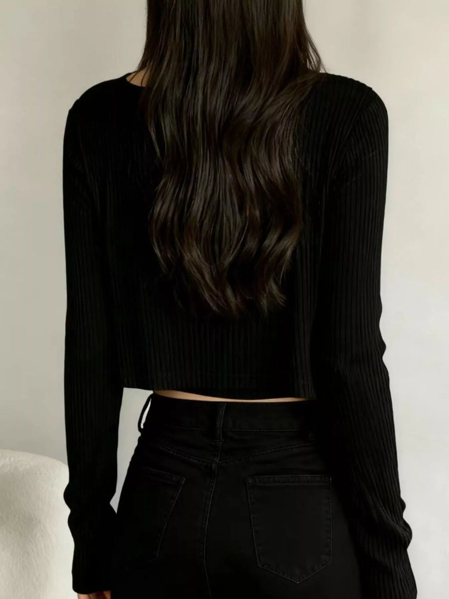 Black ribbed knit cropped cardigan with long sleeves, styled with black jeans.