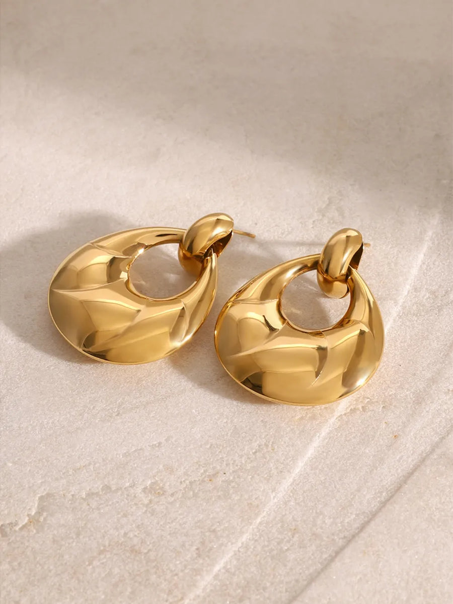 Gold statement earrings with sculpted, textured surface and open teardrop shape.