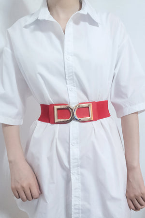 Red elastic belt with double gold buckle cinching a white dress