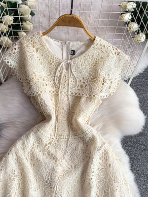 Cream lace A-line dress with short sleeves, round neckline, and tie detail.