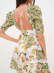 Ruched floral tie-front dress with half sleeves, lace trim, and tiered skirt.
