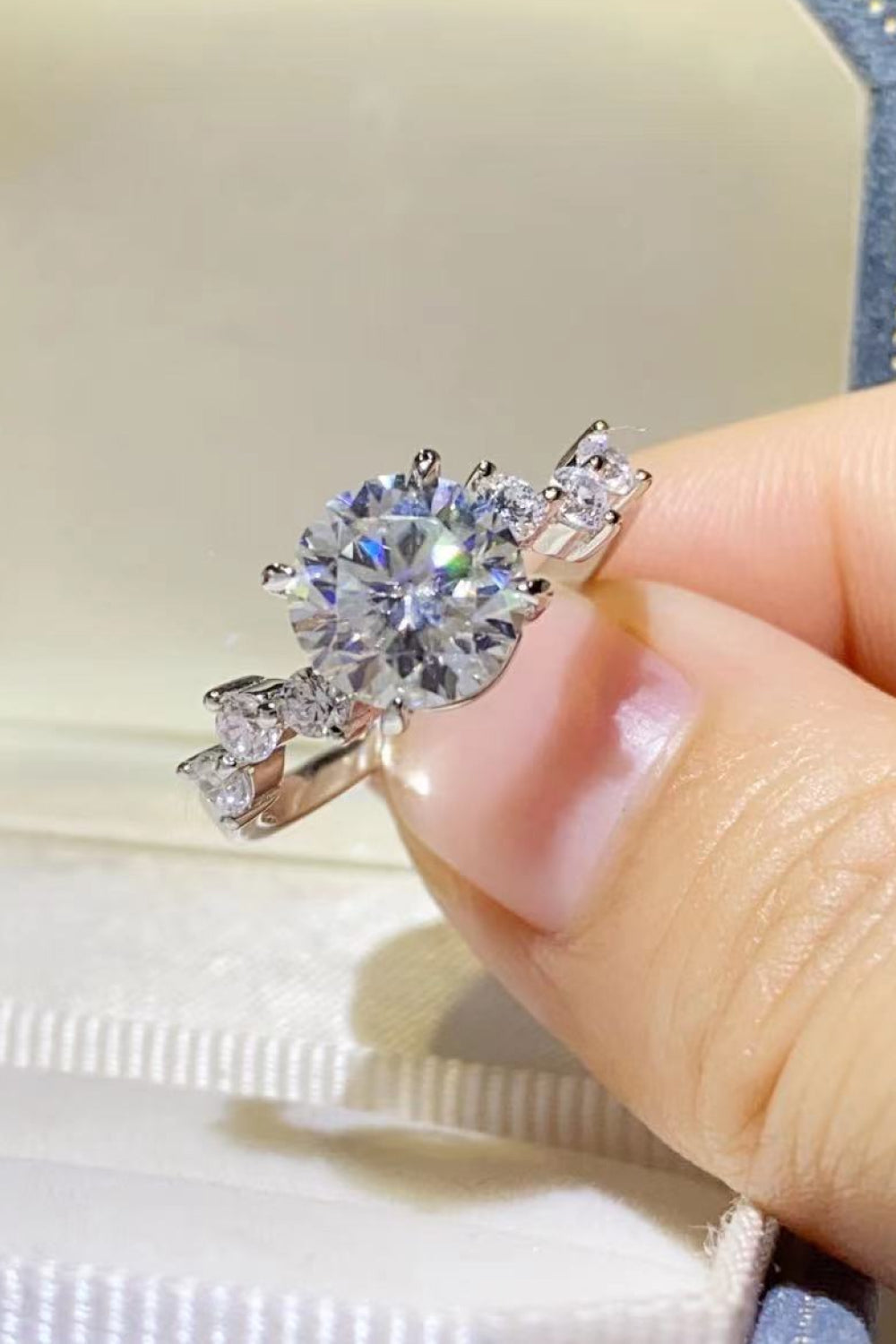 Silver moissanite halo ring with a large center stone and smaller accent stones.