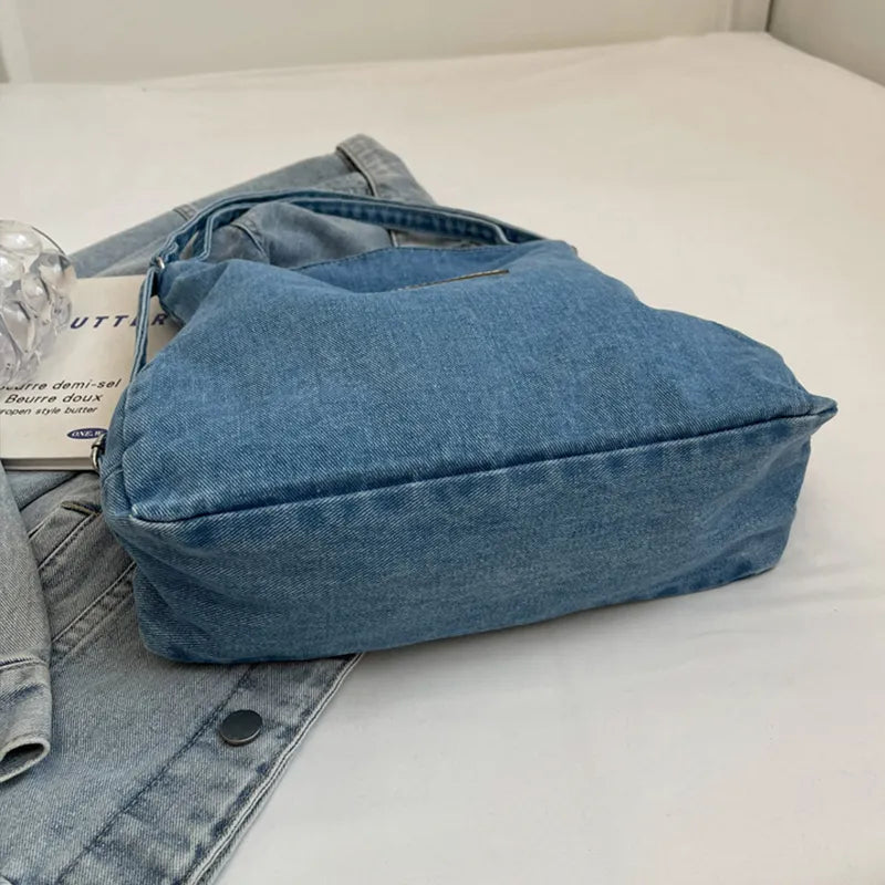 Medium wash denim hobo bag with leatherette patch detail and adjustable strap.
