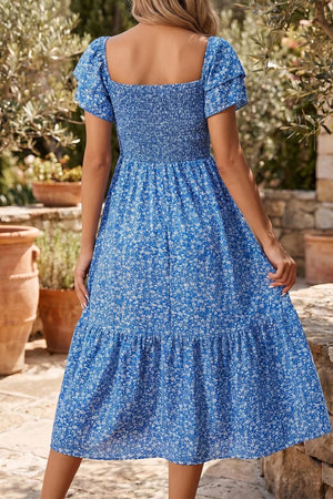 Blue floral smocked square neck dress with tiered skirt and flutter sleeves.
